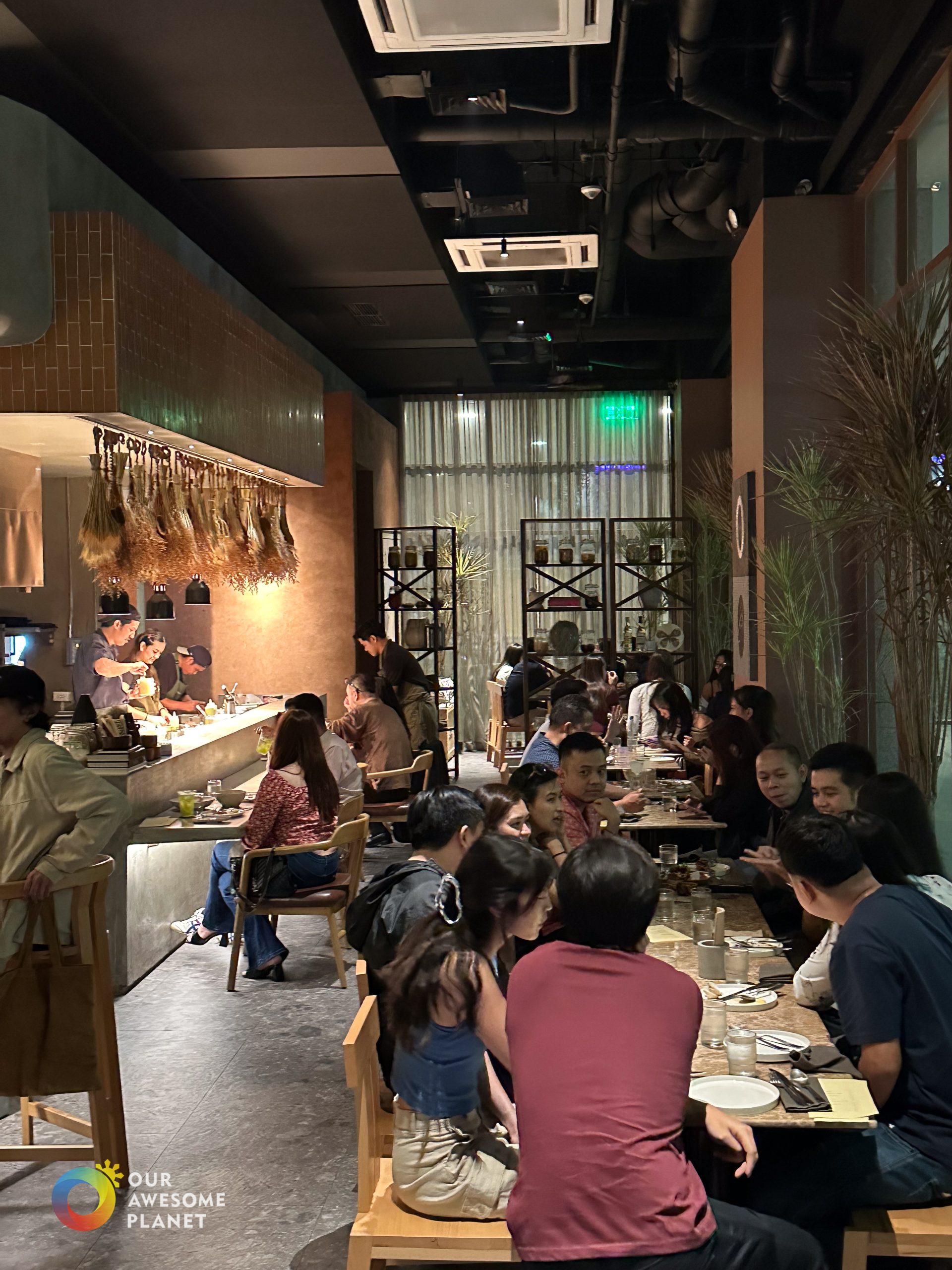 Busy interior of Los Tacos MNL during dinner service with open kitchen and guests